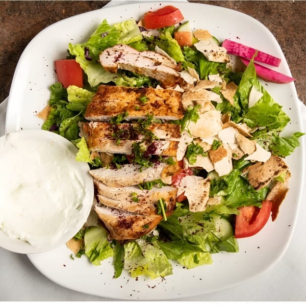 La Marra's chicken salad with lettuce, tomatoes, cucumbers, pita bread, and a side of white sauce.