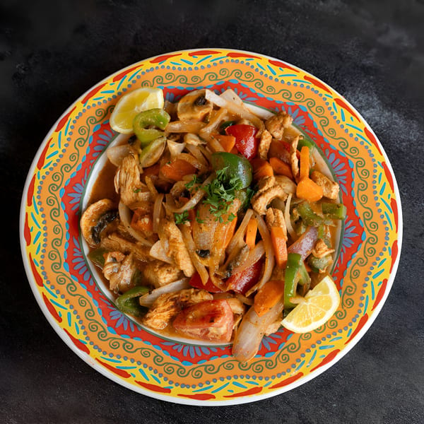 La Marra's chicken fajita with colorful vegetables, mushrooms, and lemon wedges on a vibrant plate.