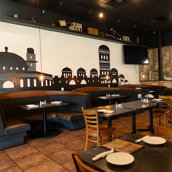 La Marra restaurant interior with booth seating, set tables, and a Middle Eastern-themed mural.