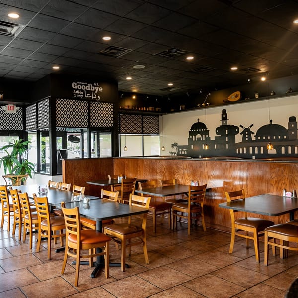 Interior of La Marra restaurant with empty tables, wooden chairs, and Middle Eastern-themed decor.